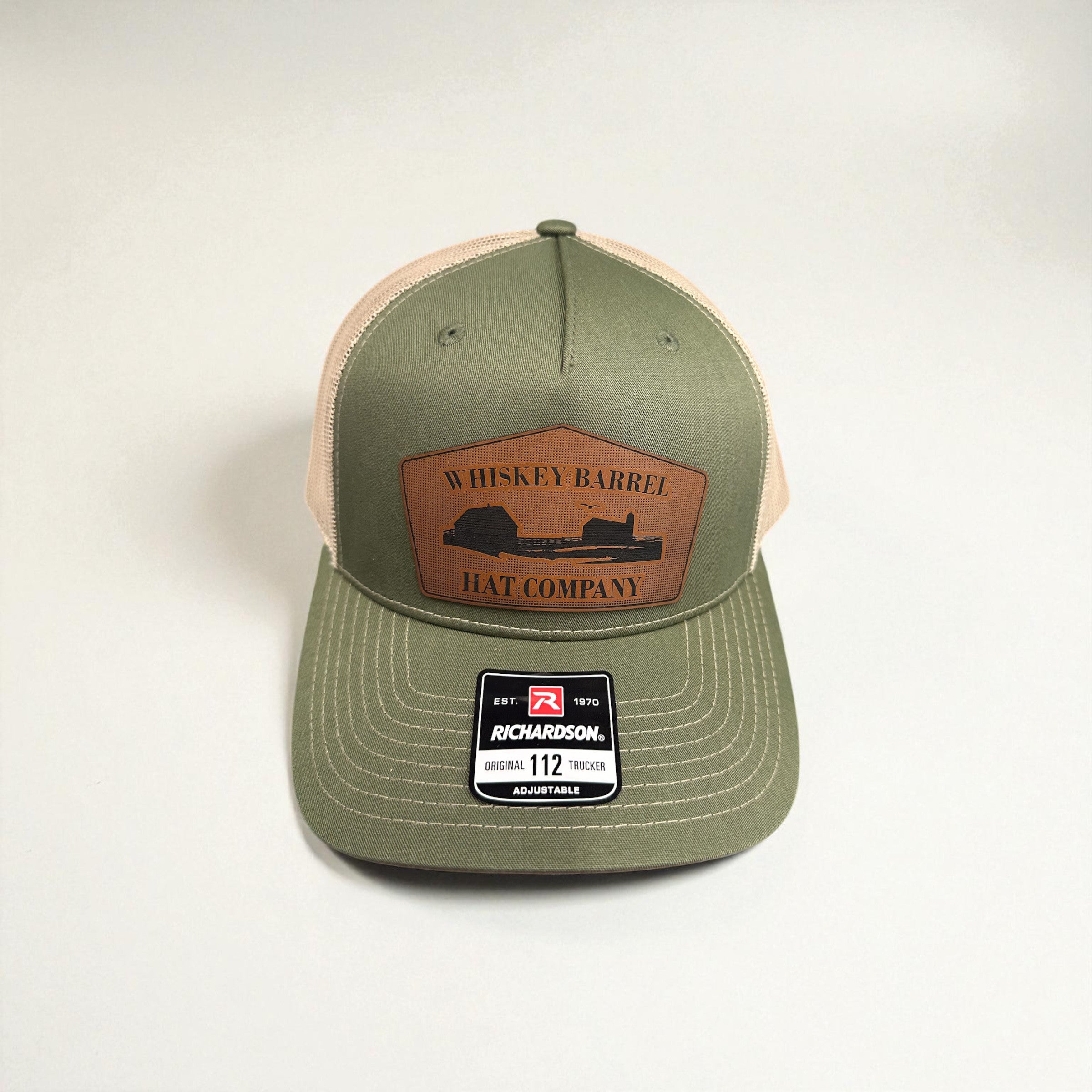 Green and beige cap with leather patch on a white background